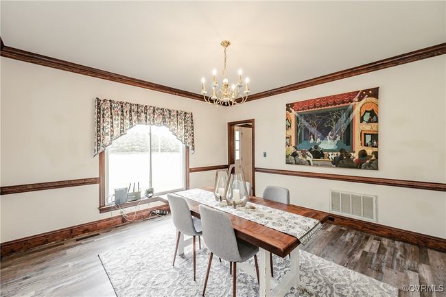 Dining area featuring a chandelier, crown molding, wood finished floors, and baseboards | Image 23