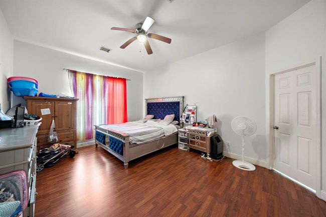 This generously sized primary bedroom offers versatility for a full suite of furnishings, with enough space for a sitting area, reading nook, or home office setup. The wood-look flooring adds a cohesive touch that flows seamlessly into the rest of the home’s updated aesthetic. | Image 15