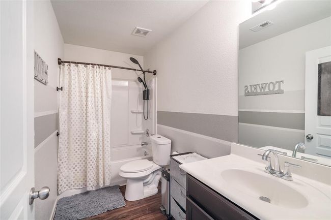 This bathroom features a stylish shower/tub combo, a dark stained vanity for ample storage, and a convenient toilet — combining function and modern design seamlessly. | Image 15