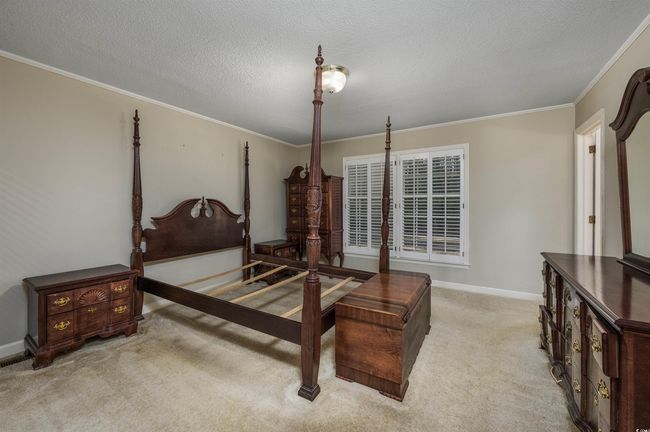 Bedroom featuring ornamental molding, light colored carpet, and a textured ceiling | Image 21