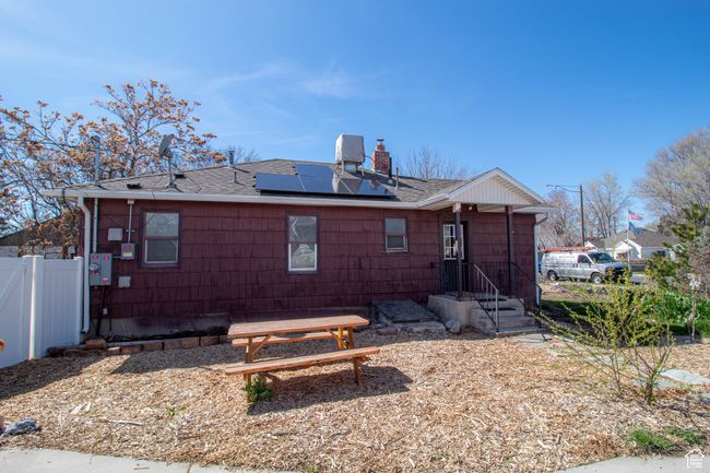 East side of property with a chimney, fence, solar panels, and roof with shingles | Image 4