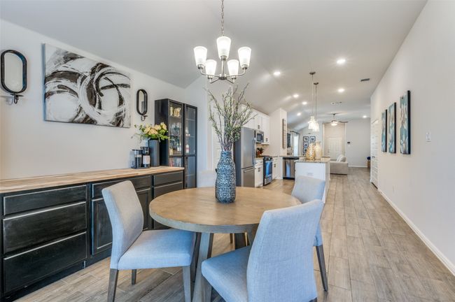 Dining room featuring an inviting chandelier, light wood-type flooring, recessed lighting, lofted ceiling, and baseboards | Image 11