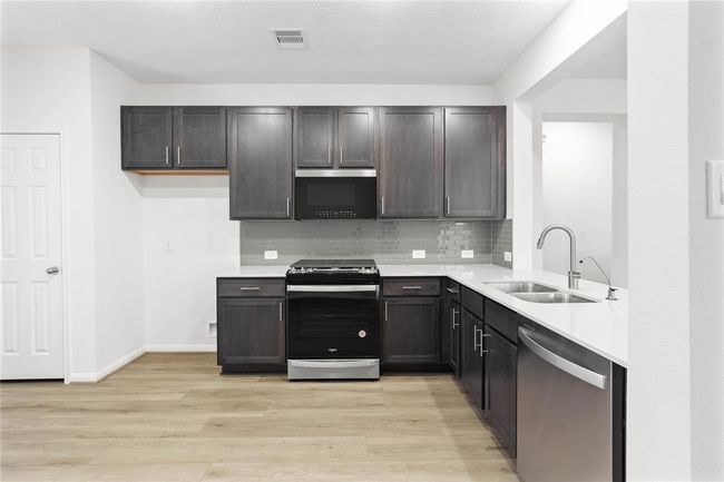 Any chef's dream, this stunning kitchen is perfect for everyday life as well as entertaining family and friends! Featuring stained cabinets, silestone countertops, modern backsplash, stainless steel appliances, recessed lighting, and custom paint. | Image 8