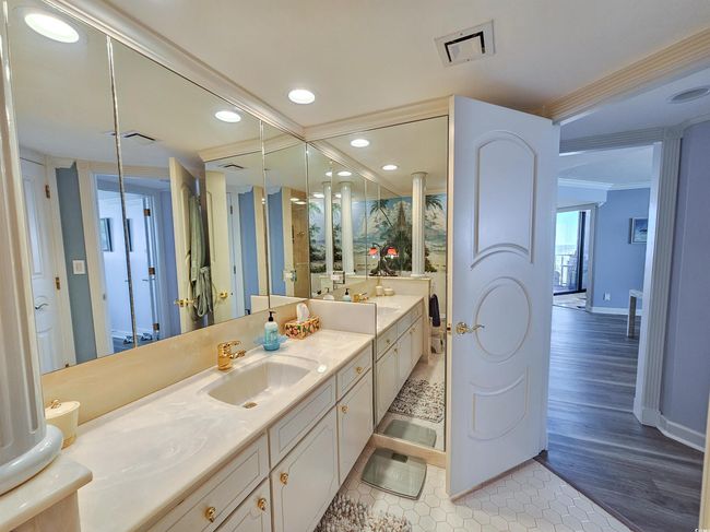 Full bathroom with crown molding, a sink, double vanity, baseboards, and visible vents | Image 36
