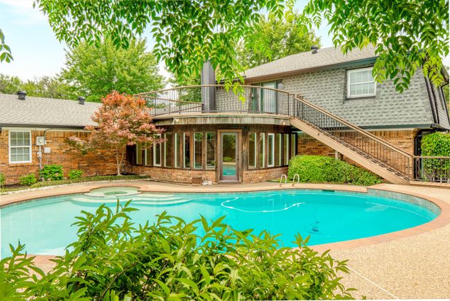 View of swimming pool featuring stairway, a sunroom, and a pool with connected hot tub | Image 38