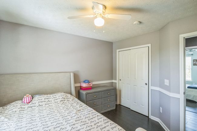 bedroom featuring dark wood finished floors, a closet, a textured ceiling, and a ceiling fan | Image 21