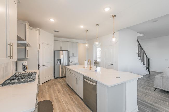 Kitchen featuring sink, an island with sink, decorative light fixtures, decorative backsplash, and appliances with stainless steel finishes | Image 10