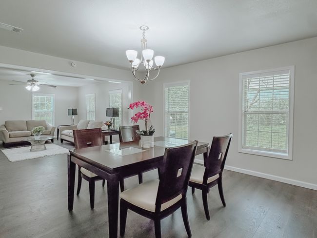 Dining space featuring wood finished floors, a chandelier, and a ceiling fan | Image 11