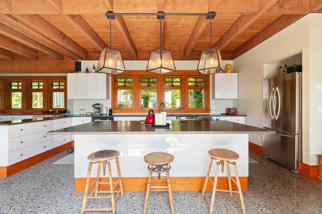 Kitchen featuring freestanding refrigerator, wooden ceiling with exposed beams, modern cabinets, white cabinetry, and speckle patterned floor | Image 8