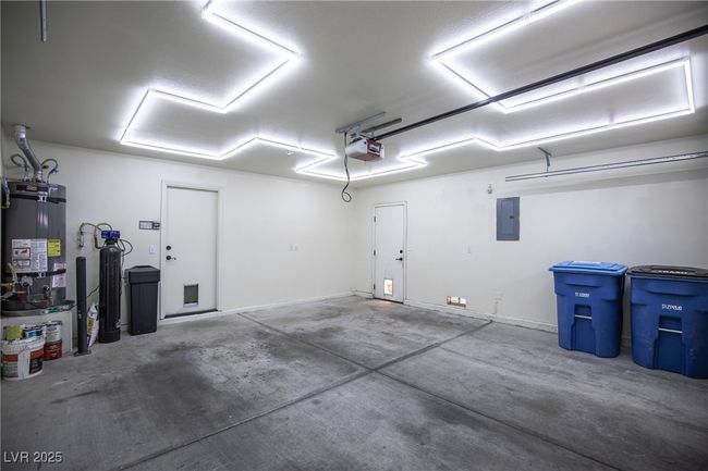 Garage with strapped water heater, a garage door opener, and electric panel | Image 28