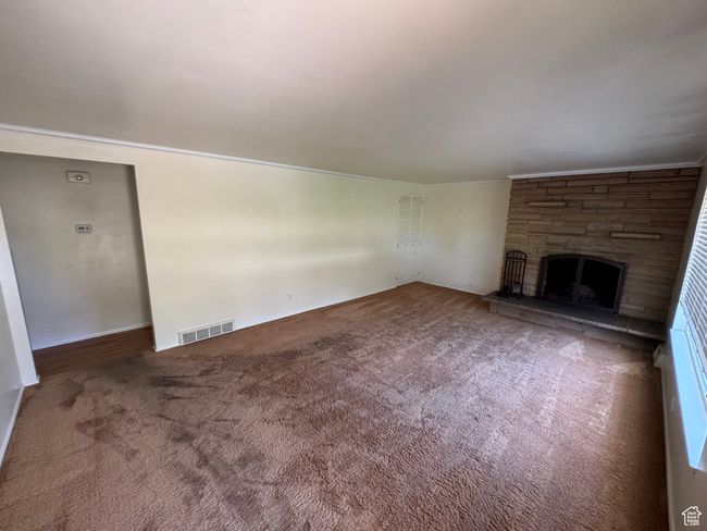 Unfurnished living room with a fireplace and carpet flooring | Image 4