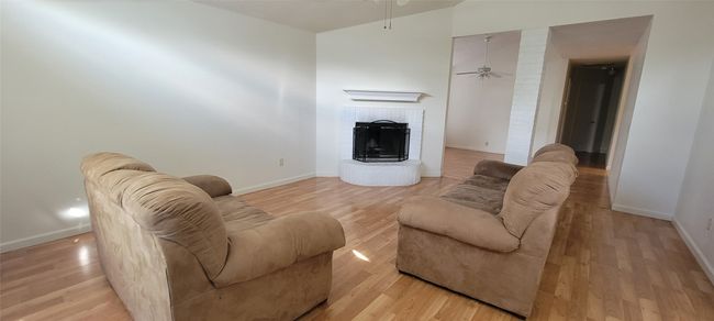 Living room featuring a ceiling fan, light wood finished floors, baseboards, and a brick fireplace | Image 6