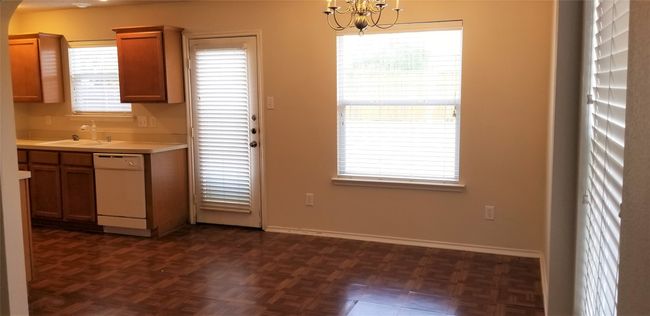 Kitchen featuring white dishwasher, a chandelier, light countertops, brown cabinets, and arched walkways | Image 9