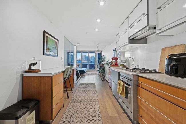 Kitchen with light countertops, white cabinetry, brown cabinets, appliances with stainless steel finishes, and light wood finished floors | Image 8