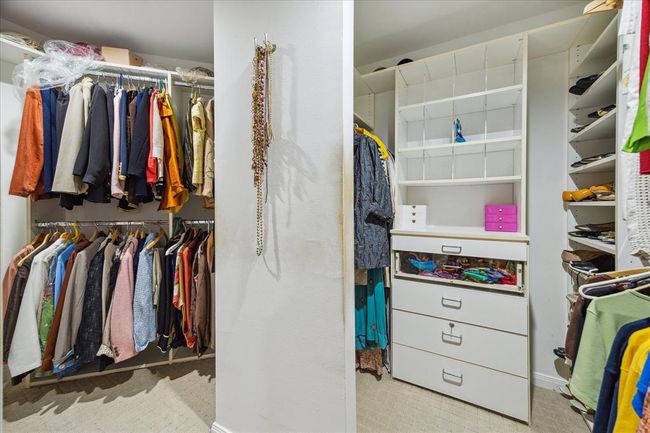 The large primary closet features built-in drawers, dedicated shoe shelves, and abundant hanging racks for optimal organization. | Image 21