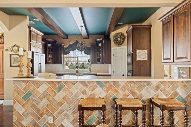 Kitchen featuring beamed ceiling, light countertops, decorative backsplash, and stainless steel appliances | Image 13