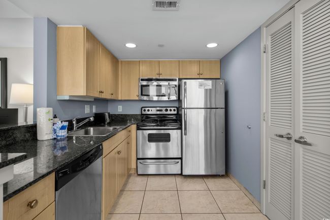 Kitchen with visible vents, light tile patterned floors, a sink, appliances with stainless steel finishes, and light brown cabinetry | Image 14