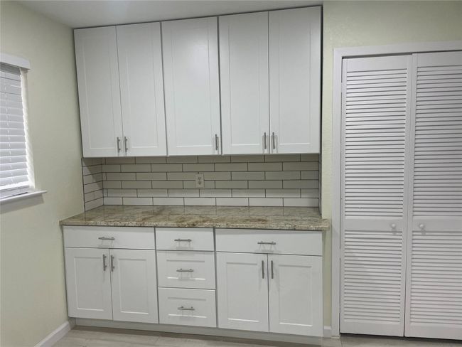 Kitchen with decorative backsplash, baseboards, light stone countertops, and white cabinets | Image 18