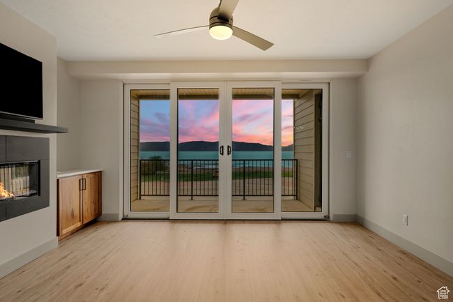Unfurnished living room featuring light wood-type flooring, a glass covered fireplace, a ceiling fan, and baseboards | Image 63