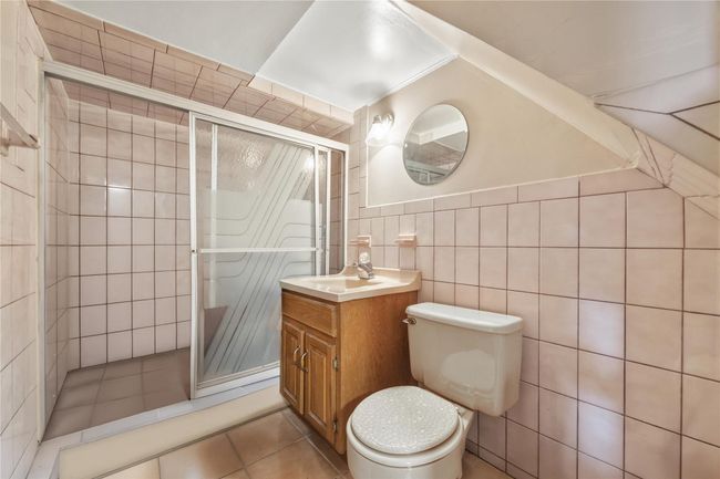 Bathroom featuring vanity, a stall shower, tile walls, and tile patterned flooring | Image 36