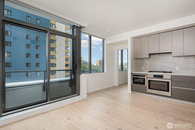 Oversized windows bring in the natural light to the spacious living room. | Image 8