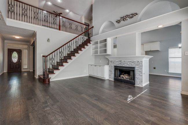 Unfurnished living room with stairway, baseboards, a tiled fireplace, dark wood finished floors, and a high ceiling | Image 7