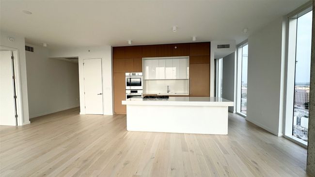 Kitchen featuring double oven, light wood finished floors, modern cabinets, and a sink | Image 15
