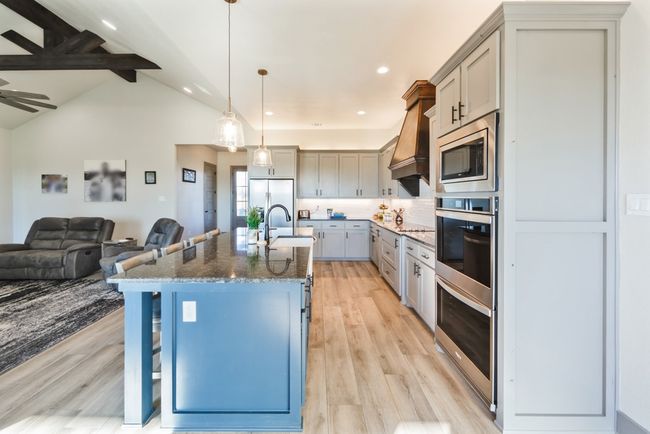 Kitchen with a breakfast bar, a sink, stainless steel appliances, open floor plan, and gray cabinetry | Image 6