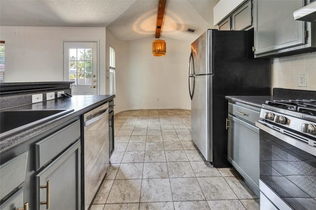 Kitchen with appliances with stainless steel finishes, dark countertops, a textured ceiling, extractor fan, and gray cabinetry | Image 7