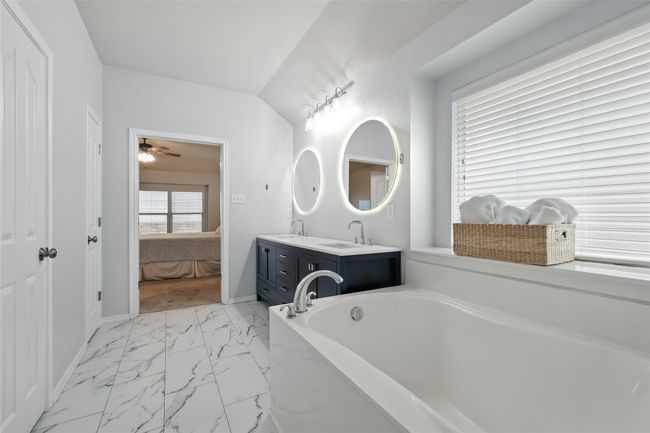 Full bathroom featuring marble look tile flooring, double vanity, a garden tub, a ceiling fan, and connected bathroom | Image 27