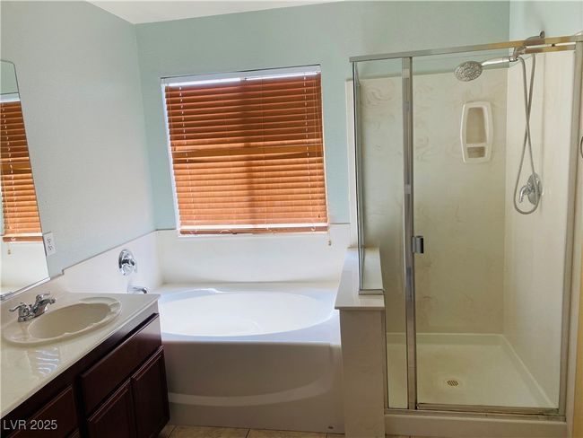 Bathroom featuring vanity, a garden tub, a stall shower, and tile patterned flooring | Image 14