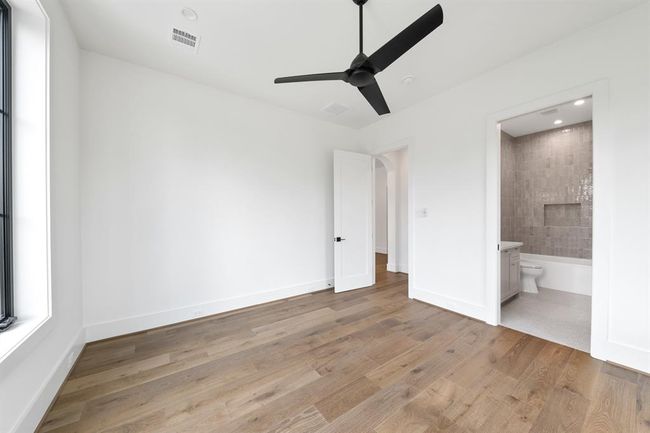One of five thoughtfully designed secondary bedrooms, this upstairs suite features generous proportions, wide-plank white oak flooring, and abundant natural light. The ensuite bath continues the elevated aesthetic with designer tile, modern fixtures, and a seamless walk-in shower. | Image 32