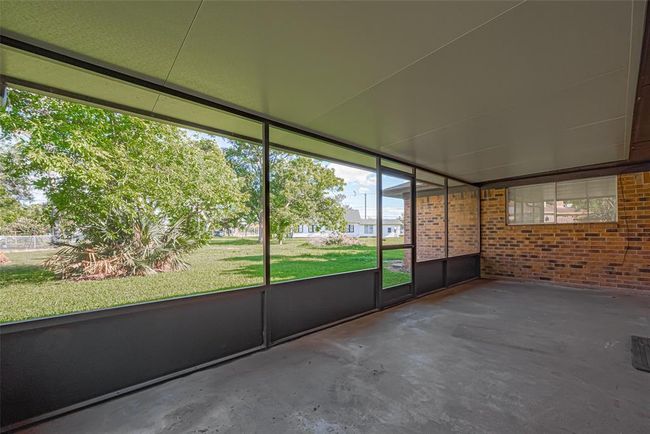 Leading out of living area, covered back patio offers plenty of space for outdoor activities and relaxation, with a view of the backyard through screened panels. Enjoy the beauty of your backyard rain or shine! | Image 26