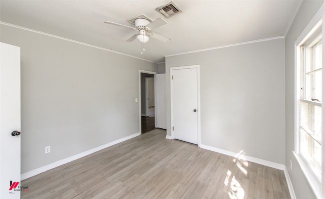 Unfurnished bedroom featuring baseboards, ornamental molding, visible vents, and light wood-style floors | Image 10