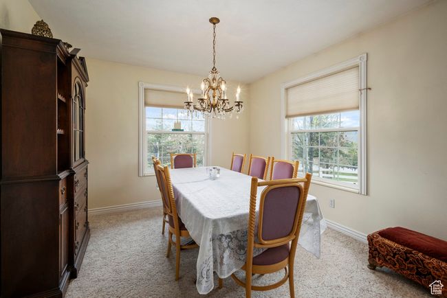 Dining space with a notable chandelier, light carpet, and a healthy amount of sunlight | Image 13