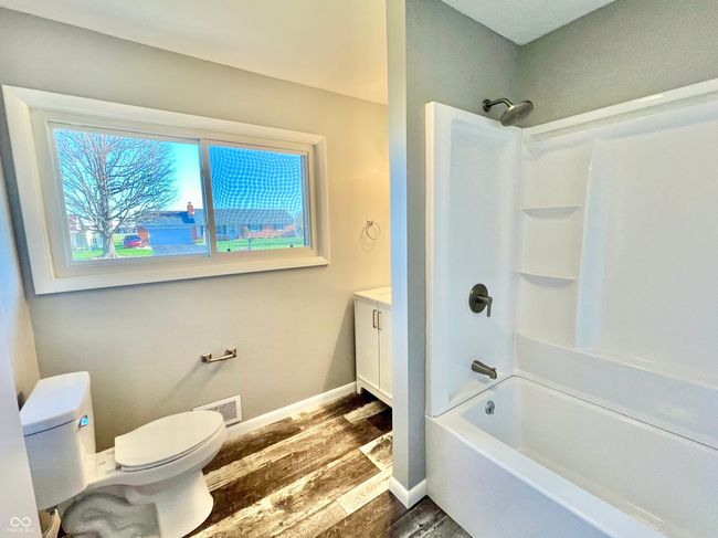 bathroom with visible vents, baseboards, shower / washtub combination, toilet, and wood finished floors | Image 15