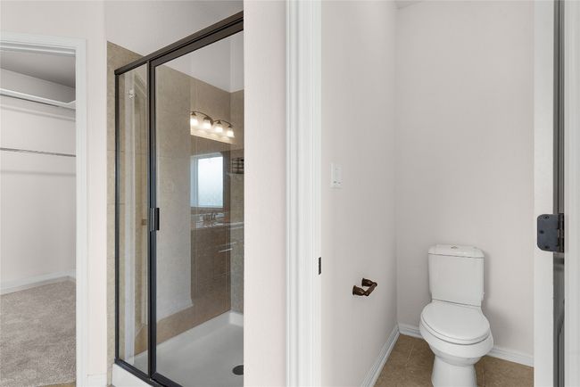 Bathroom featuring tile patterned flooring, a walk in closet, baseboards, toilet, and a stall shower | Image 33
