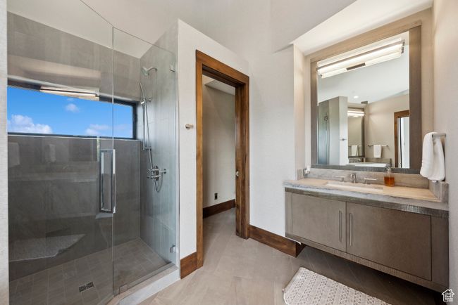 Bathroom with a stall shower, vanity, baseboards, and tile patterned flooring | Image 45