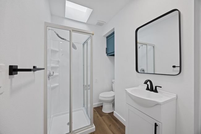 Full bathroom with a stall shower, vanity, wood finished floors, and a skylight | Image 15