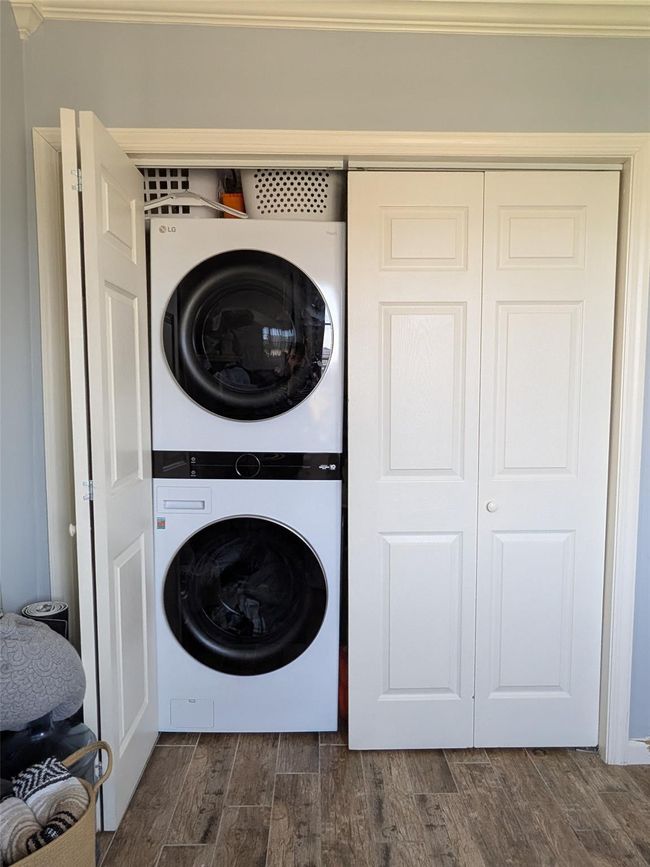 Laundry featuring stacked washer and dryer and dark wood finished floors | Image 17