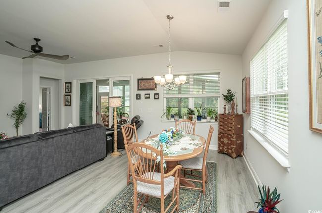 Dining room featuring light wood-style flooring, a chandelier, lofted ceiling, ceiling fan, and baseboards | Image 26