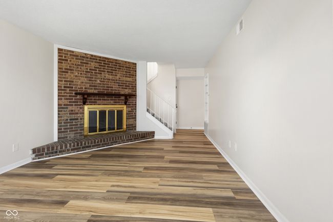 unfurnished living room with a fireplace, visible vents, wood finished floors, and baseboards | Image 4