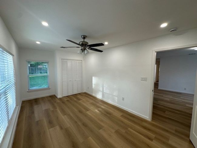 Unfurnished bedroom with wood finished floors, baseboards, recessed lighting, ceiling fan, and a closet | Image 20