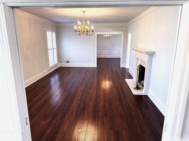 Unfurnished living room with ornamental molding, dark wood-type flooring, a chandelier, and a high end fireplace | Image 8