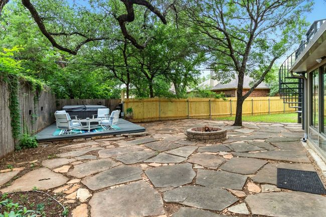Step outside to your very own backyard oasis. Enjoy evenings around the custom flagstone fire pit, take a soak in the hot tub on its dedicated wooden deck, or dine under the stars on the spacious patio. The oversized side yard offers room for games, pets, or gardening, all under the shade of mature trees | Image 21