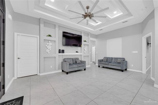 Living room with ceiling fan, a raised ceiling, built in features, a high ceiling, and recessed lighting | Image 8