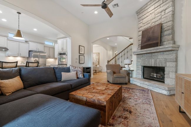 Living area with a ceiling fan, arched walkways, light wood finished floors, recessed lighting, and a stone fireplace | Image 7