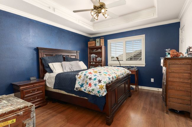 Bedroom witt wood-type flooring, a raised ceiling, crown molding, and ceiling fan | Image 22