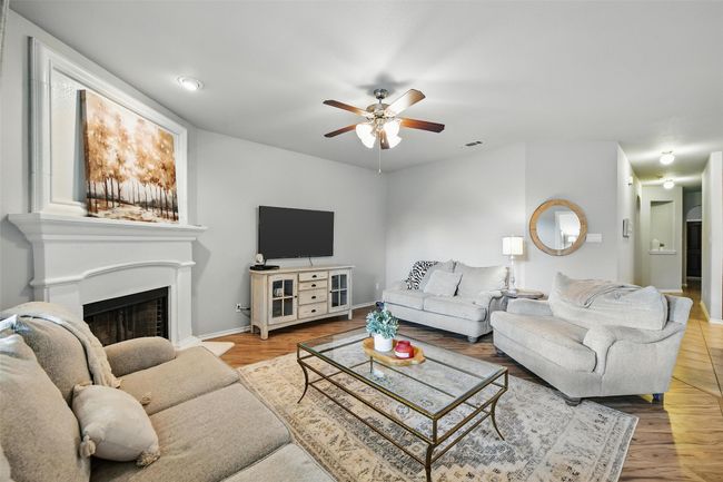Living area featuring ceiling fan, a fireplace with raised hearth, and wood finished floors | Image 17