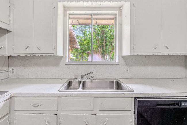 Kitchen with black dishwasher, light countertops, and white cabinets | Image 17